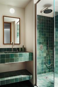 a bathroom with a shower with green tiles at Edgar Suites - Bouchardon in Paris