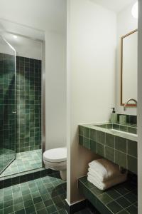 La salle de bains est pourvue de toilettes et d'une douche avec du carrelage vert. dans l'établissement Edgar Suites - Bouchardon, à Paris