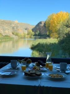 a table with plates of food and a view of a lake at Casitas del MolinoGrande in San Miguel de Bernúy