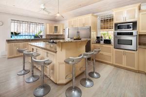 eine Küche mit Holzschränken und Barhockern in der Unterkunft Arcadia Blue Sky Luxury in Bridgetown
