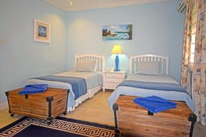 una camera con due letti e un tavolo con una lampada di Arcadia Blue Sky Luxury a Bridgetown