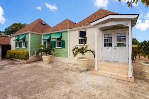 ein grünes Haus mit Palmen davor in der Unterkunft Arcadia Blue Sky Luxury in Bridgetown