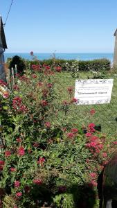 un jardin avec des fleurs rouges et un panneau sur celui-ci dans l'établissement Le clapotis de l'Ô, calme, balcon sur la mer, à 2 h de Paris, à Ault