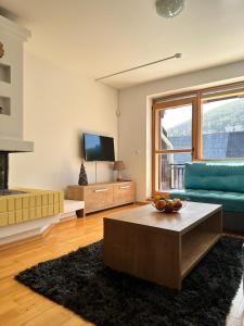 a living room with a blue couch and a television at BJELAŠNICA BEX APARTMANI 