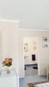 een witte kamer met een vaas met bloemen op een tafel bij The Lady Grace in Greyton
