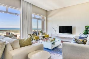 ein Wohnzimmer mit einem Sofa und einem TV in der Unterkunft Bakoven Sunsets - Luxury Apt with sea views & pool in Kapstadt