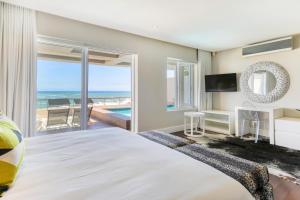 a bedroom with a bed and a view of the ocean at Bakoven Sunsets - Luxury Apt with sea views & pool in Cape Town