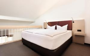 una camera da letto con un grande letto con lenzuola bianche di Donna Hotel Klosterhof a Neukirchen beim Heiligen Blut