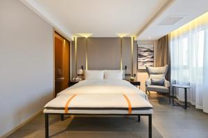 - une chambre avec un grand lit et une chaise dans l'établissement Atour Hotel Shenyang Nanta Wenhua Road, à Shenyang