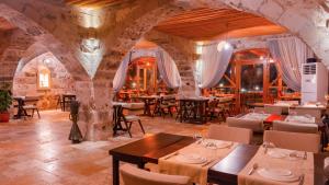 a restaurant with tables and chairs in a stone building at La Fairy Cappadocia in Uçhisar