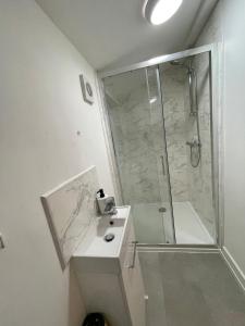 een badkamer met een douche en een wastafel met een glazen douchecabine bij Neath 4 Bedroom Whole Home Haven Steps from Town Sleeps 7 in Aberdulais
