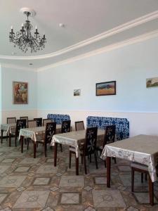 uma sala de jantar com mesas e cadeiras e um lustre em Демалыс үйі Риза Гостевой дом em Vorobʼyëvka