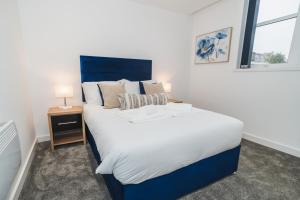 een slaapkamer met een groot bed met een blauw hoofdeinde bij VICHY - The Thornhill City Center Apartment in Wakefield