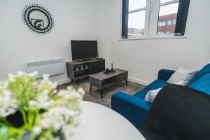 a living room with a blue couch and a tv at VICHY - The Thornhill City Center Apartment in Wakefield