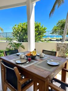 a wooden dining table with a view of the ocean at Cosy studio - 2P - Orient Bay - ALAMANDA - 002 in Saint Martin