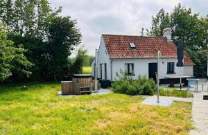 una pequeña casa blanca en un campo con un patio en Sauna-Garden en Blankenberge