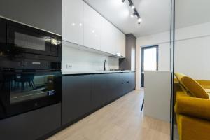 a kitchen with black and white appliances and a yellow couch at Vanda in Bucharest
