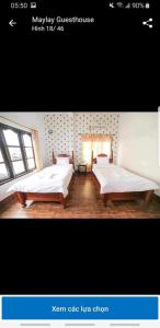 two beds in a room with two windows at Maylayguesthouse1 in Vang Vieng