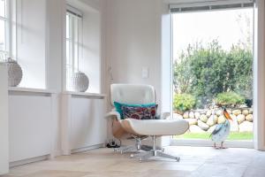 een witte stoel in een kamer met een raam bij Ferienhaus Heidehüs Mellhörn in List