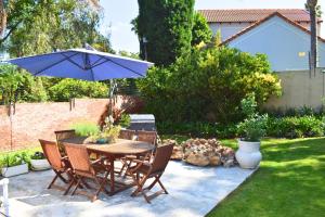 a patio with a table and chairs and an umbrella at Riverclub Guest Suites in Riverclub, Sandton in Johannesburg