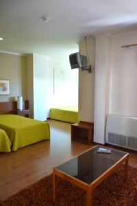 ein Wohnzimmer mit einem Bett und einem Couchtisch in der Unterkunft Hotel Gameiro in Entroncamento