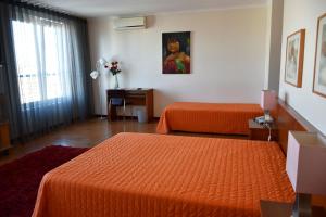 a bedroom with two beds and a desk and a window at Hotel Gameiro in Entroncamento +33 photos