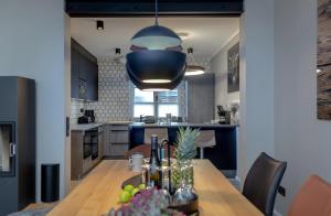 une cuisine et une salle à manger avec une table et une lampe suspendue bleue dans l'établissement Ferienhaus am Buttgraben, à List auf Sylt