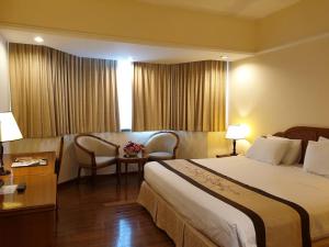 ホーチミン・シティにあるRamana Saigon Hotelのベッド、テーブル、椅子が備わるホテルルームです。