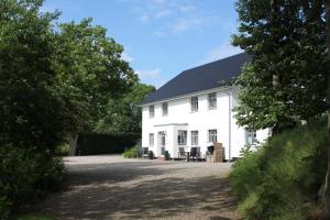 uma casa branca com um telhado preto em Ferienwohnung 'Falshöft' - Refugium Pottloch Ostsee em Kronsgaard