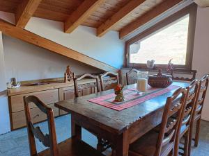 een eetkamer met een houten tafel en stoelen bij La dzenta méizón in Villeneuve