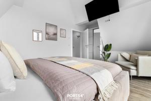 ein weißes Schlafzimmer mit einem Bett und einer Couch in der Unterkunft Ferienwohnung Inselfeeling Fehmarn in Fehmarn