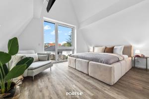 ein weißes Schlafzimmer mit einem großen Bett und einer Couch in der Unterkunft Ferienwohnung Inselfeeling Fehmarn in Fehmarn