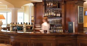 a man standing behind a bar with bottles of alcohol at Victor's Residenz-Hotel Erfurt in Erfurt