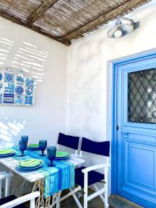 uma sala de jantar com mesa e cadeiras e uma porta azul em LemonStello Kythnos em Dhriopís