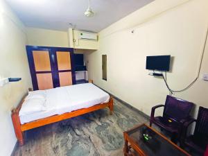 a small room with a bed and a tv at STAYMAKER Unnatha Residency in Manipal