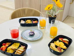 a table with two trays of breakfast food and orange juice at The Host apartamentos At Los Angeles in Santa Marta