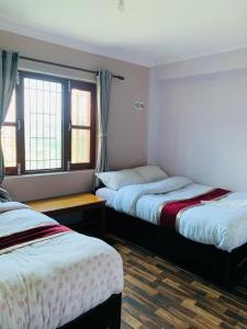 twee bedden in een kamer met twee ramen bij Bandipur Samira Homestay - Experience the Best for Less in Bandipur