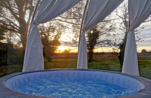 a hot tub in a tent with the sunset in the background at Buby - végtelenbe és tovább in Szigetvár +14 photos