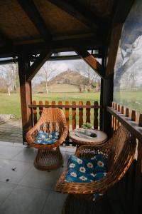 2 Korbstühle und ein Tisch auf einer Veranda in der Unterkunft Kuća za odmor Ana in Josipdol