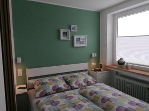 1 dormitorio con cama y pared verde en Ferienwohnung Astenrefugio, en Winterberg