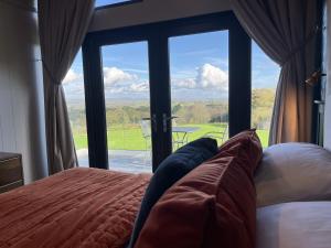um quarto com uma cama e uma grande janela de vidro em Warren Farm Retreat - Pod 1, Pod 2, and The Lodge by SSW em Cardiff