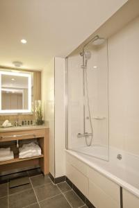 a bathroom with a shower and a tub and a sink at City Résidence Paris CDG Airport in Roissy-en-France