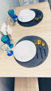 une table avec deux assiettes blanches et des verres bleus dans l'établissement Апартаменты на Бурова, à Öskemen