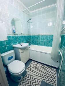 La salle de bains est pourvue de carrelage bleu, de toilettes et d'un lavabo. dans l'établissement Апартаменты на Бурова, à Öskemen