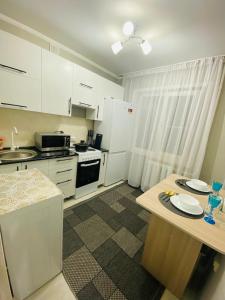une cuisine avec des placards blancs et une table avec des assiettes. dans l'établissement Апартаменты на Бурова, à Öskemen