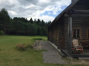 una cabaña de madera con un banco y una silla al lado en Vällamäe talu puhkemaja, en Haanja