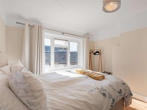 a bedroom with a white bed with a window at 3 Bed in Swanage 84019 in Swanage