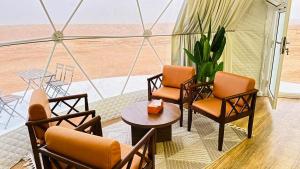 Habitación con sillas, mesa y vistas al desierto en Starry Domes Desert Camp II, en Badīyah