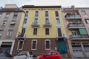 a yellow building with cars parked in front of it at I Host Apartment - Carcano 26 in Milan
