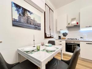 uma cozinha branca com uma mesa de jantar e cadeiras em mazzini101apartment em Ferrara